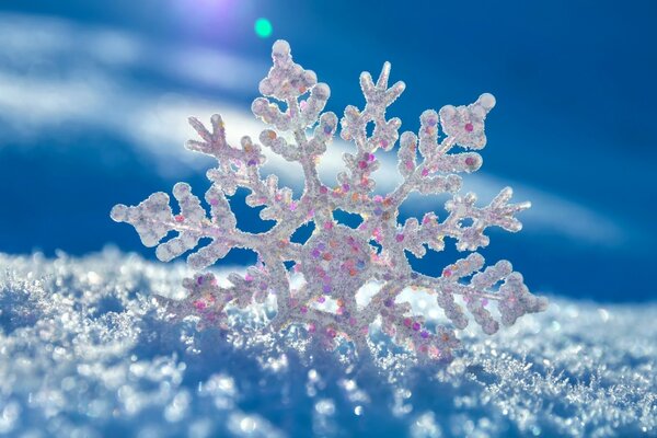 Sparkling snowflake on white snow