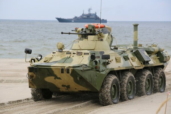 A battle tank near the water rides on the sand