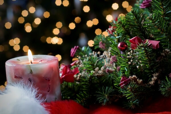 Brennende Kerze neben dem geschmückten Weihnachtsbaum