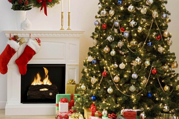 Un elegante árbol de Navidad regalos debajo de ella y una chimenea con calcetines