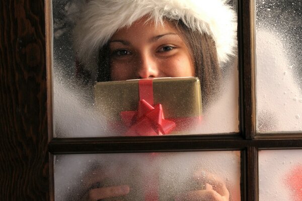 Das neue Jahr und das Mädchen vor dem Fenster mit einem Geschenk