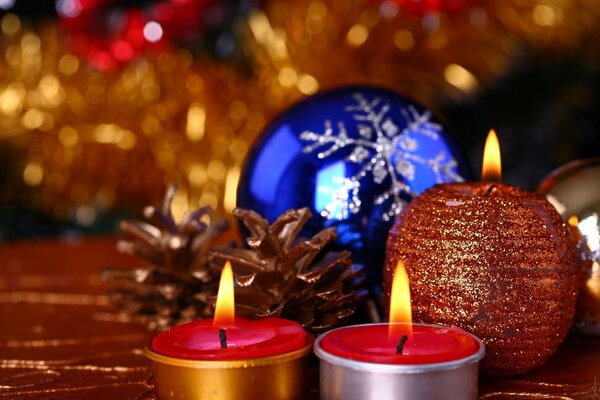 Three candles and a blue Christmas ball on a red background