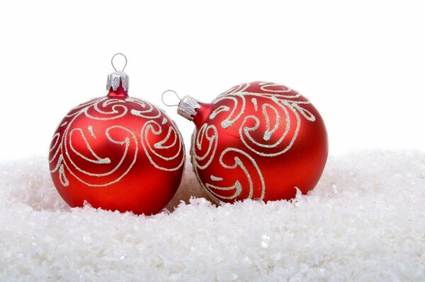 Два красных новогодних шарика на снегу
