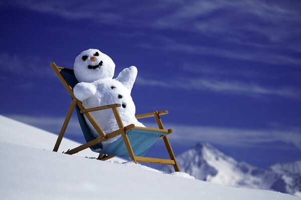 Neujahr , Schneemann im Sessel und im Hintergrund von Bergen und Schnee