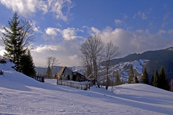 Paesaggio invernale con montagne innevate e una casa solitaria