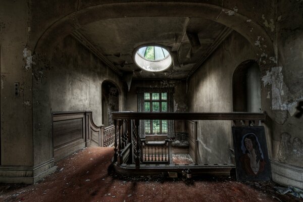 Ventana redonda sobre una escalera antigua en una mansión abandonada