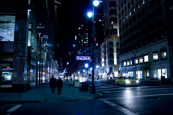 Die Leute kommen, ein Taxi fährt durch eine ruhige Nachtstraße