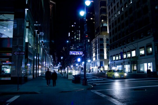 Les gens marchent, un taxi roule dans une rue calme de nuit