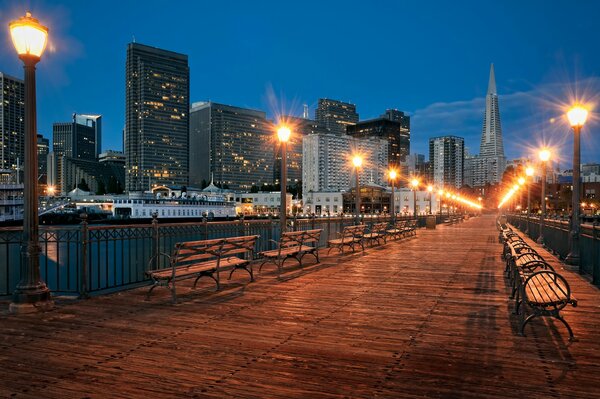 A walking bridge and benches against the background of city lights