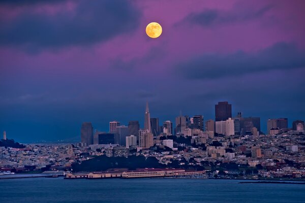 Round moon in the blue sky above the city