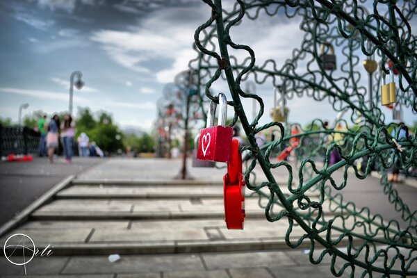 Serrures rouges avec un coeur accroché sur un pont