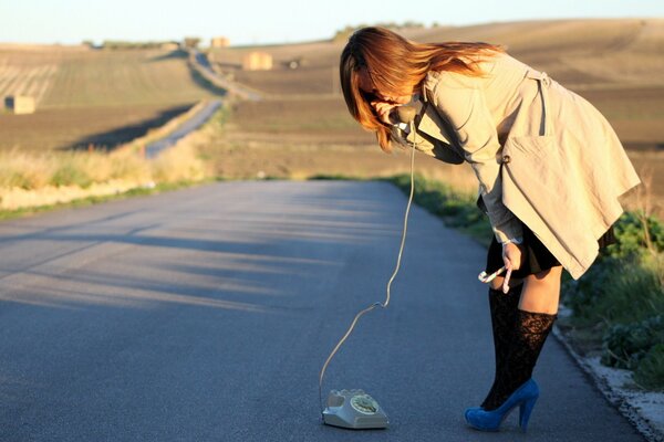 A girl with a landline phone on the road
