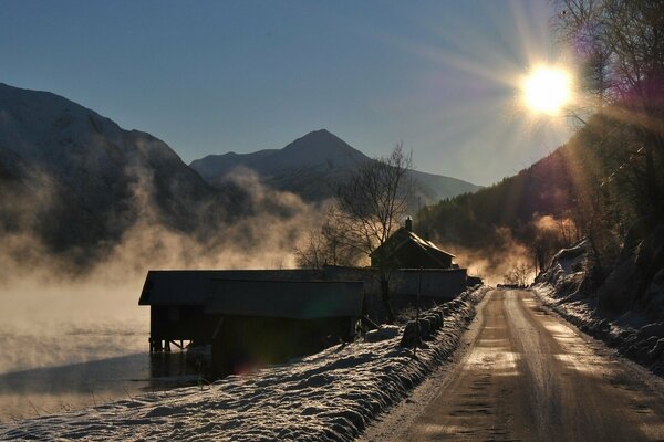 Sole dolce che illumina la strada invernale che corre vicino al lago