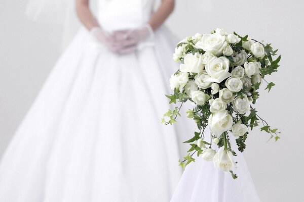 Weißer Rosenstrauß auf dem Hintergrund des Brautkleides