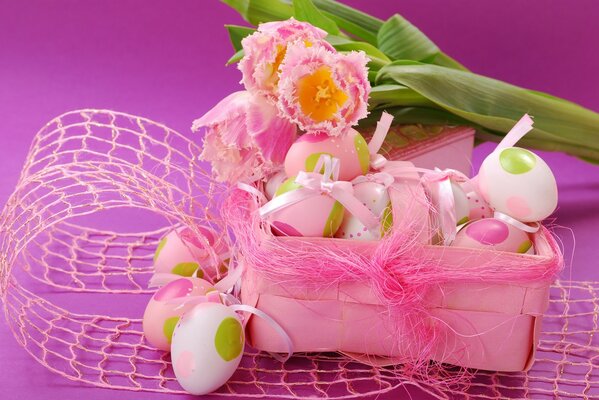 Oeufs de Pâques dans une boîte et trois tulipes dans des tons roses