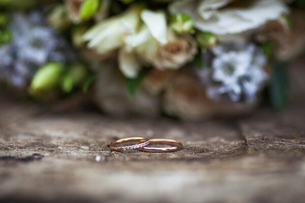 Zwei goldene Ringe Nahaufnahme auf einem zarten Blumenstrauß Hintergrund