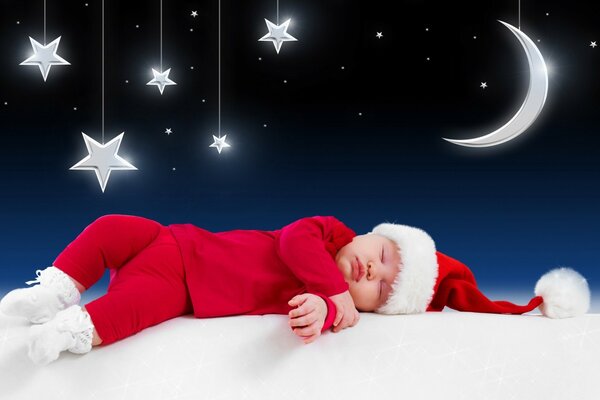 Piccolo bambino in costume da Babbo Natale che dorme sotto il cielo stellato