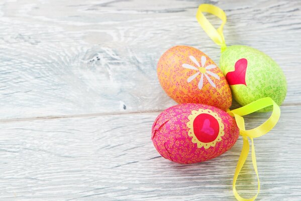 Tres huevos de Pascua multicolores con cintas amarillas