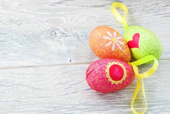 Tre uova di Pasqua colorate con nastri gialli