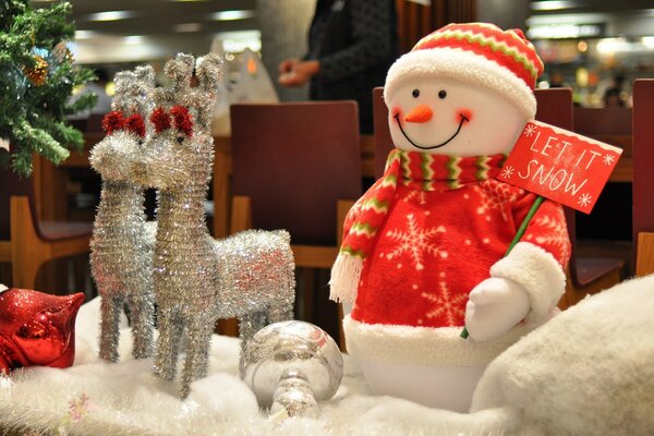 Muñeco de nieve con renos cerca del árbol de Navidad