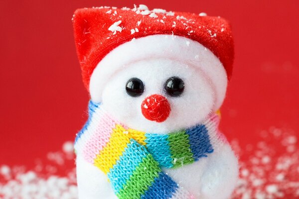 New Year s red background souvenir snowman in uniform and scarf on artificial snow