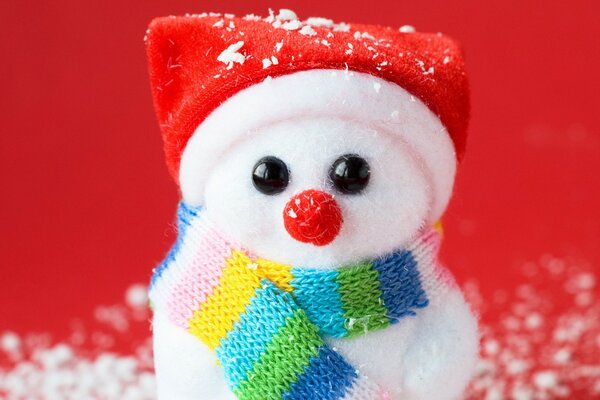 Natale sfondo rosso pupazzo di neve souvenir in uniforme e sciarpa sulla neve artificiale