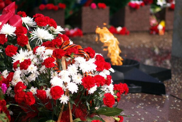 Fiamma eterna con cesto di fiori in primo piano