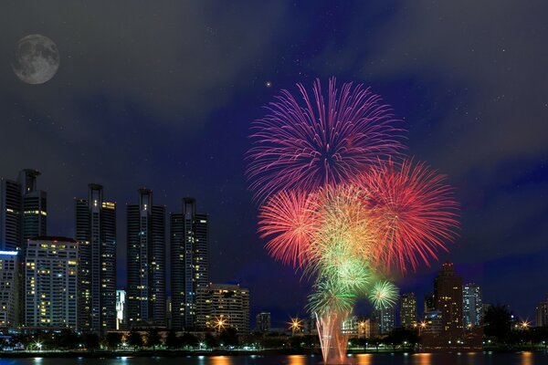 Fuegos artificiales de colores en el fondo del cielo lunar y la ciudad