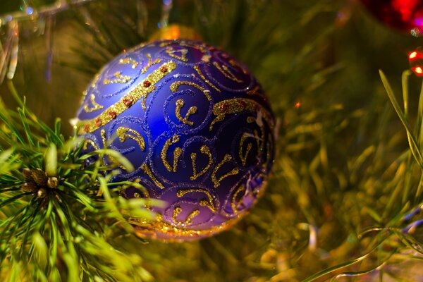 A blue Christmas tree toy with a golden pattern weighs on the Christmas tree