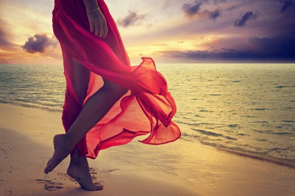 Hermosas piernas en el fondo de la puesta de sol del mar