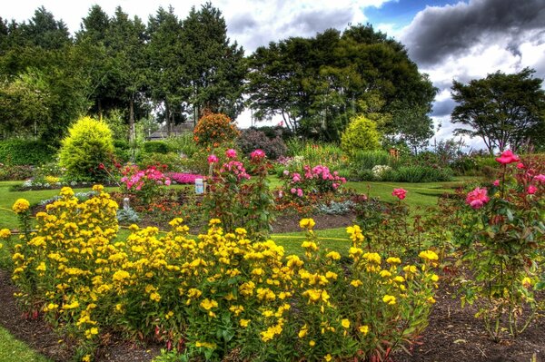 Schöner Garten mit Bäumen und hellen Blumen