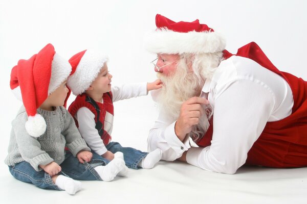 Der Weihnachtsmann kommuniziert mit zwei Kindern in roten Mützen