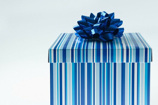Boîte-cadeau élégante. Rayures bleu-blanc-bleu sur la boîte. Grand arc bleu. Bonne année