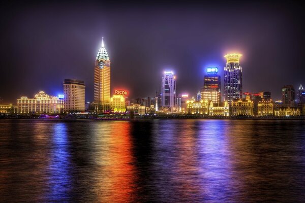 Nachtlandschaft mit Lichtern in den Fenstern und ihrer Reflexion im Wasser