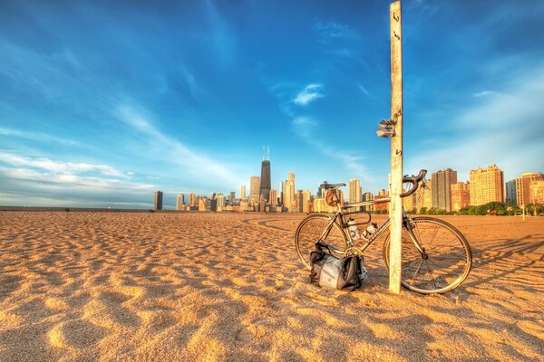Пляж, на нем столб, к которому прислонен велосипед