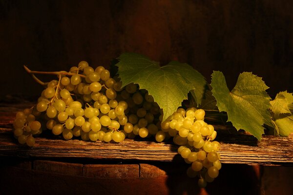 Bunches of white grapes with leaves on a wooden table