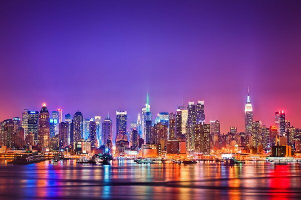 Las luces de la noche de Manhattan se reflejan en el río Hudson