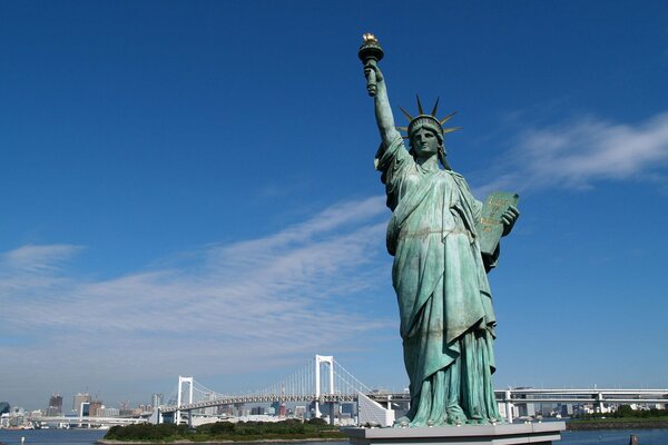 Enorme estatua de la libertad en el fondo de un puente en la ciudad de nueva York