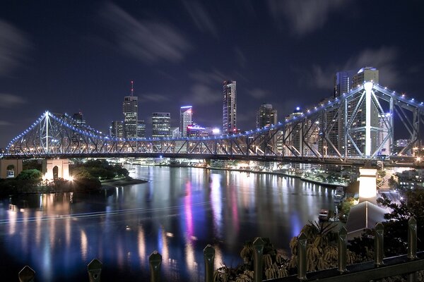 Leuchtende Lichter auf der Brücke. Häuser und Wolkenkratzer am Fluss der Nachtstadt