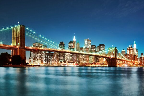 Puente de Brooklyn en la noche, en el fondo de la ciudad en las luces