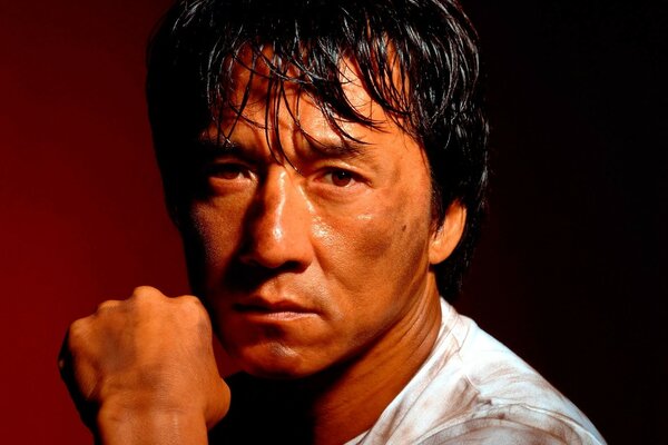 Jackie Chan est assis avec un poing dans la main