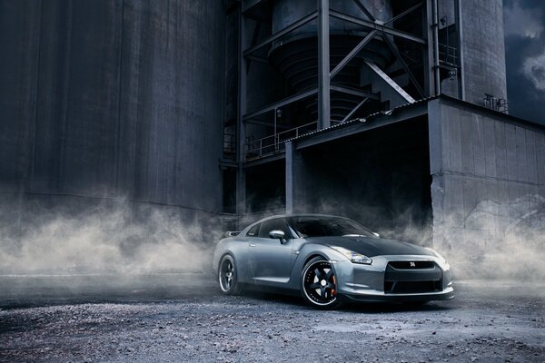 Nissan in smoke on the background of the plant among gravel