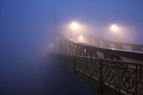 Puente a través de la niebla en el azul de la mañana