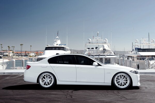 Białe BMW na tle białych jachtów
