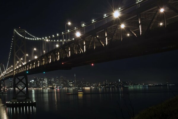 Las brillantes luces nocturnas en el puente se reflejan en el río