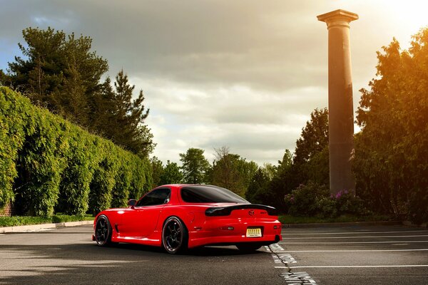 Rouge Mazda rx-7 dans le parking entre les arbres