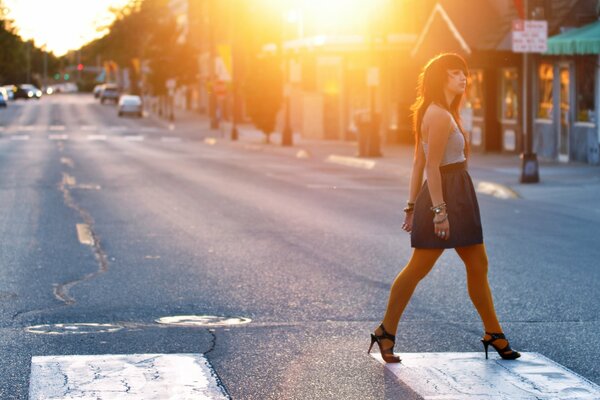 Fille marchant de l autre côté de la rue dans les rayons du soleil du soir