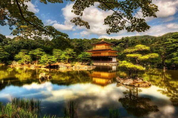 Золото пагод японского храма отражается в водах и облаках
