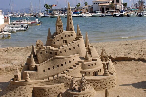 Castello di sabbia sullo sfondo di yacht e stagno