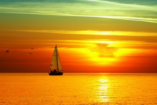 Und das Segelboot segelte in den orangefarbenen Sonnenuntergang